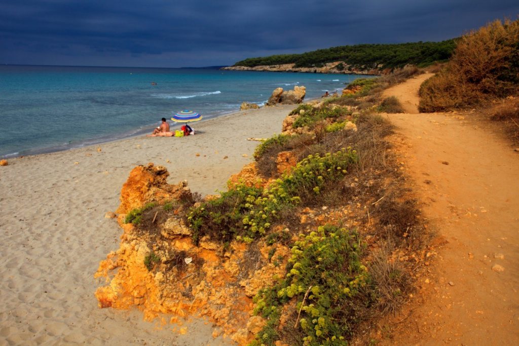 Turistická stezka podél nádherné pláže Santo Tomás na Menorce.